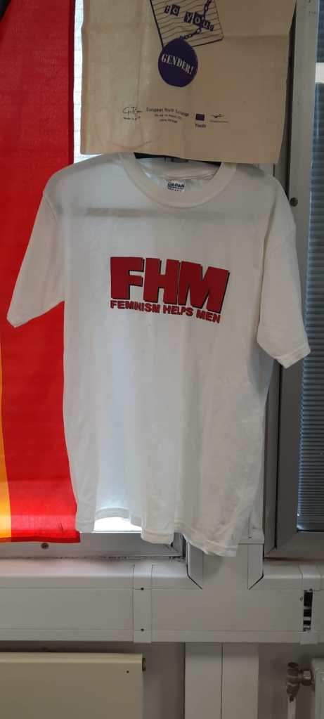 Photo of a t-shirt bearing the slogan FHM: Feminism Helps Men.